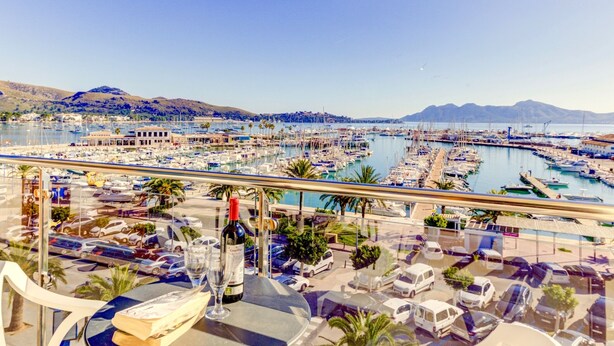 Un puerto deportivo con barcos, vista al puerto y un balcón con mesa y sillas.