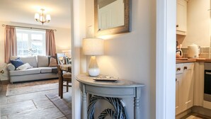 A living room with a sofa, a dining table, and a lamp. There is a kitchen area with cabinets and a countertop. - Manor Barn Cottage (Bakewell)