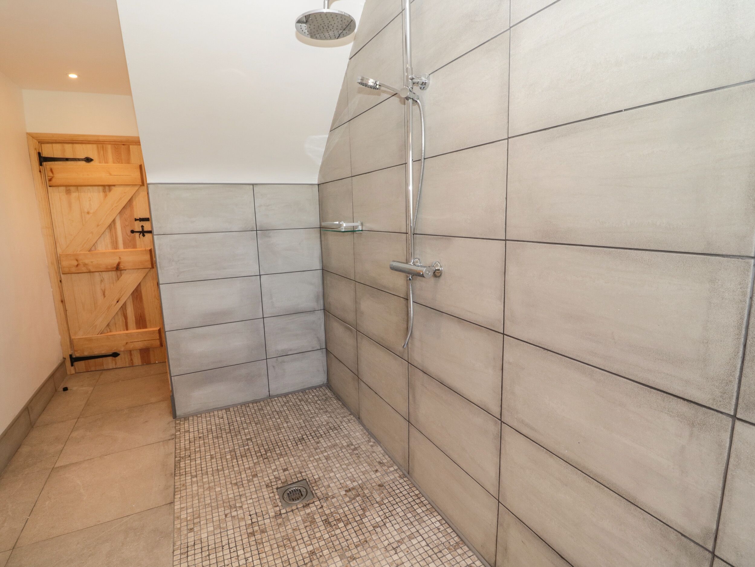 A shower area with tiled walls and a wooden door.