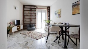 A modern living room with a TV, sofa, dining table, and a bookshelf. - Italianway Easy - Sirte 6 (Milan)