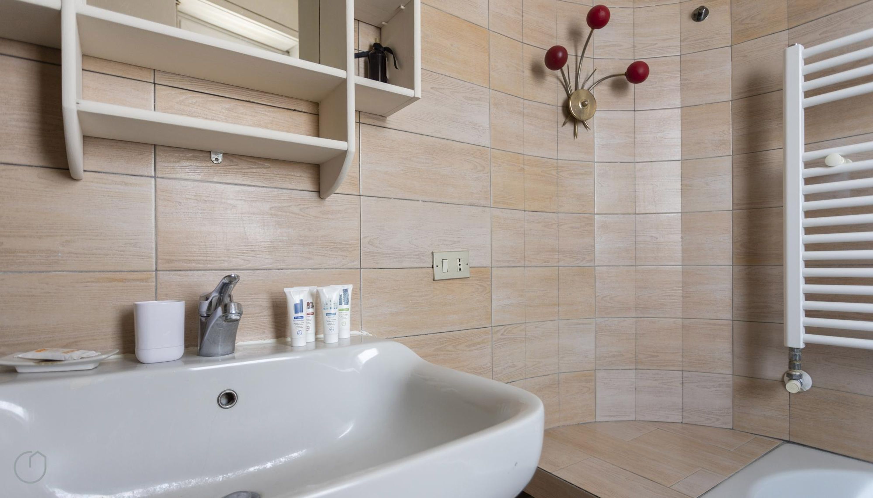 A bathroom with a white sink, a mirror, and a shower area.