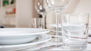 Une table dressée avec des assiettes blanches, un verre d’eau et un verre à vin.