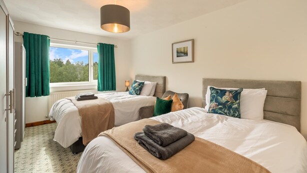 A hotel room with two beds, a window with curtains, a ceiling light, and a framed picture on the wall. - Trefelyn Cottage in Saundersfoot (Saundersfoot)