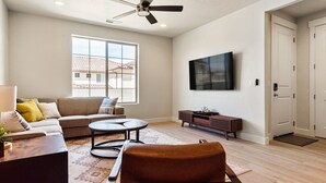 Ein geräumiges Wohnzimmer mit einer Couch, einem Couchtisch und einem an der Wand befestigten Fernseher.