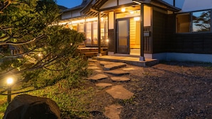 A traditional Japanese-style building with a wooden entrance and a stone pathway leading to the door. - Toya Cliff House (Toyako)