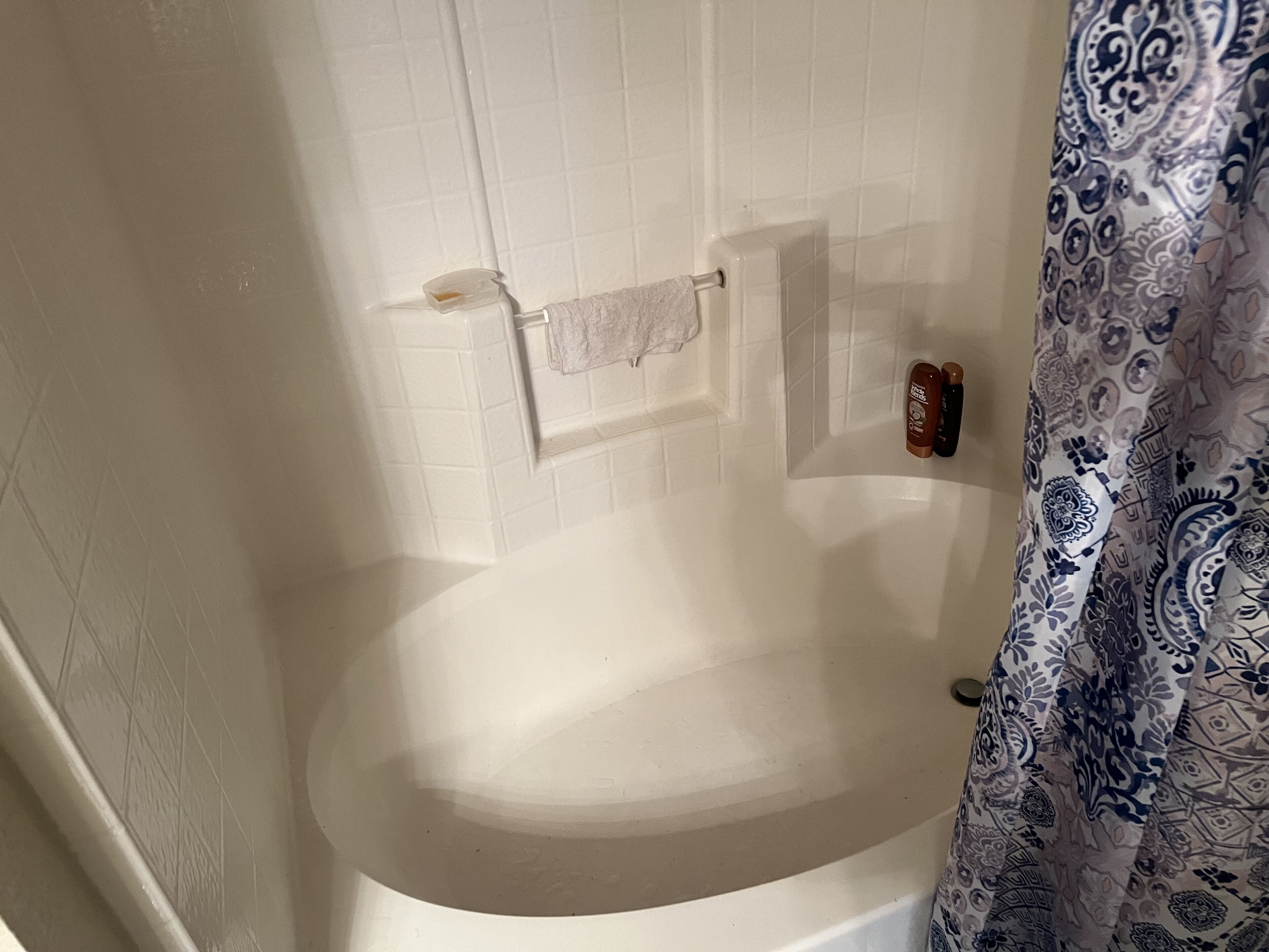 Um banheiro com banheira, porta-toalhas e cortina de chuveiro.