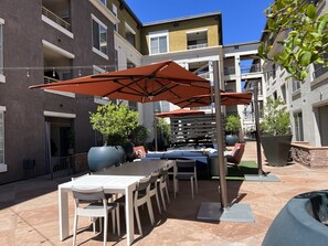 An outdoor patio area with a table and chairs, a large umbrella, and potted plants. - SPACIOUS [1 bedroom] {3mins} : ((Topanga / Westfield Mall)) ! (Glendale)