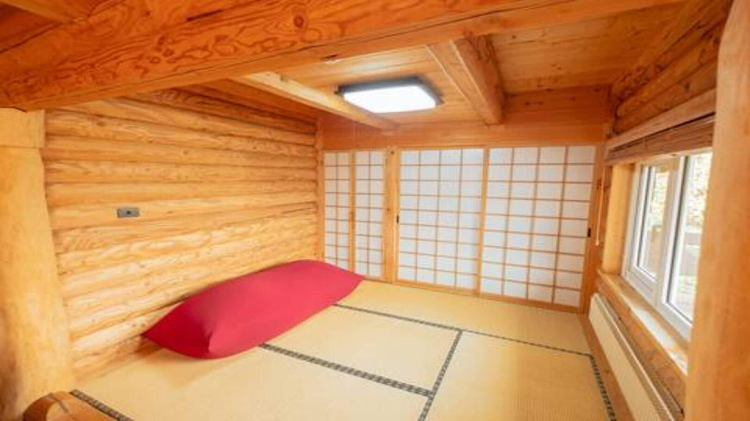 A traditional Japanese-style room with tatami flooring, a low wooden ceiling, and a sliding shoji screen door.