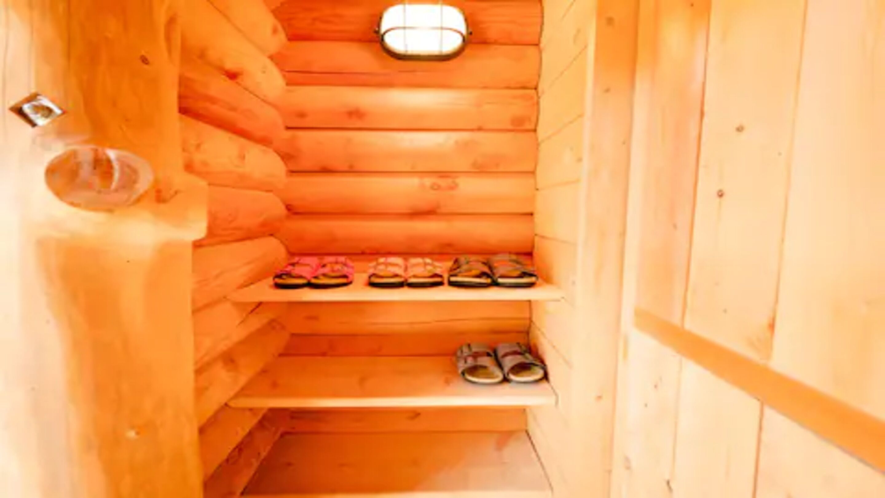 Una sauna de madera con un banco y estantes para zapatos.