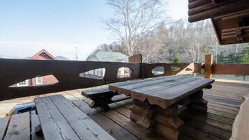 Una terraza de madera con una mesa de picnic y bancos.