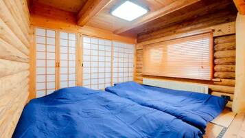 Een houten kamer met een bed, een raam met zonwering en een dakraam.