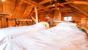 Eine Holzhütte mit zwei Betten, einer Holzzahlendele und einem kleinen Tisch.