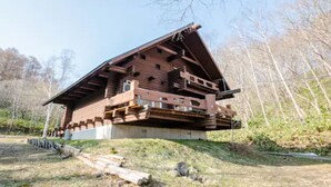 Eine Holzhütte mit geneigtem Dach und einem Balkon, umgeben von Bäumen.