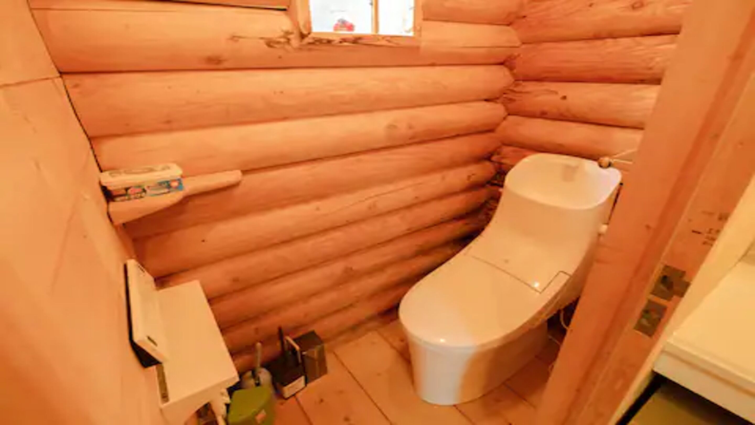 A small, compact wooden cabin-style bathroom with a toilet and a sink.