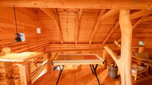 Ein rustikaler Blockhaus-Innenraum mit Holztisch, Pendelleuchte und kleinem Fernseher.