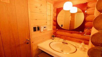 Un baño de madera con un espejo redondo, lavamanos y un perchero para toallas.