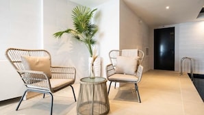Een modern interieur met twee rieten stoelen, een glazen tafel en een potplant.