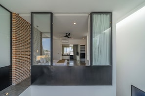 Een modern interieur met een grote schuifpui, een bakstenen muur en een plafondventilator.