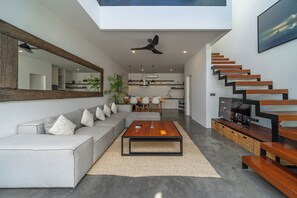 A modern living room with a sectional sofa, a coffee table, and a staircase.