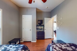 Two single beds with matching headboards, a flat-screen TV, and a bookshelf create a cozy retreat.