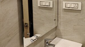 Un baño con lavamanos blanco, un espejo y un perchero para toallas.