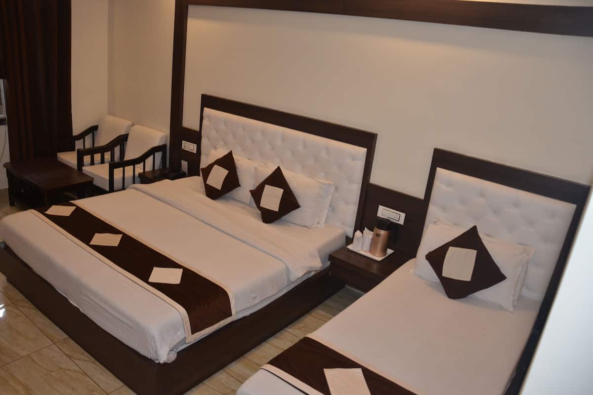Una habitación de hotel con dos camas, una mesita de noche, una silla y una pequeña mesa.