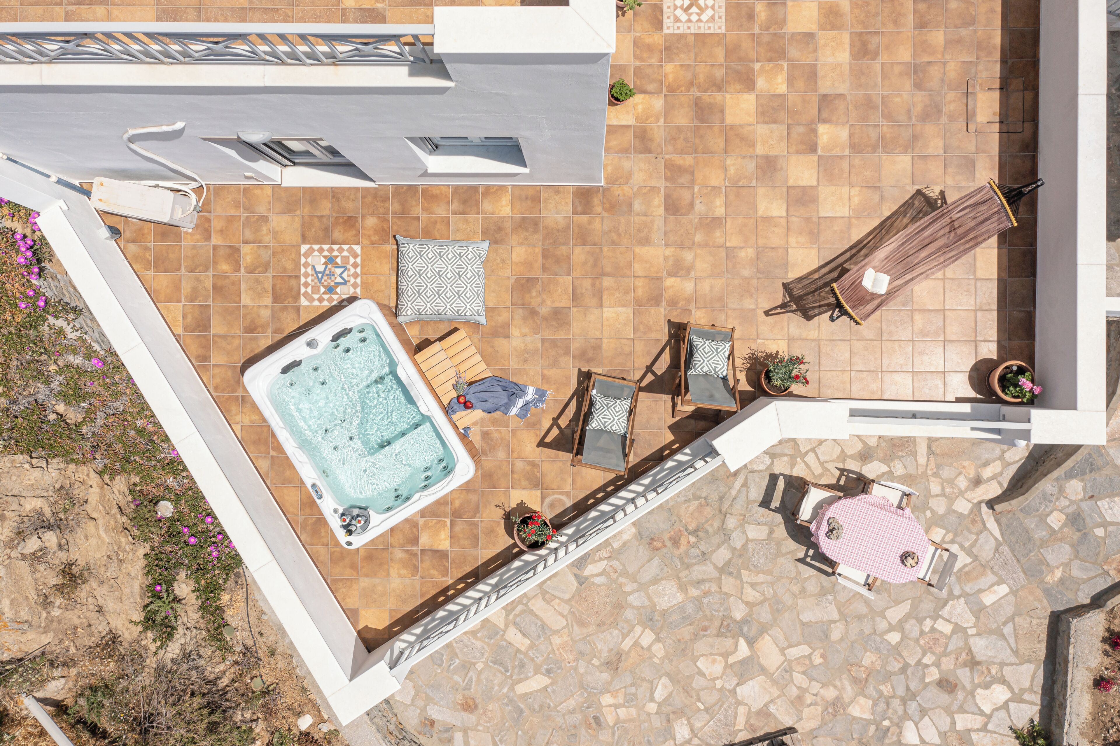 A rooftop terrace with a hot tub, seating area, and potted plants.