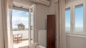 Une chambre à coucher avec un lit, une armoire en bois et une vue sur la mer par la fenêtre.