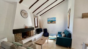 Una sala de estar con chimenea de piedra, televisor, sofá azul y una mesa de centro.