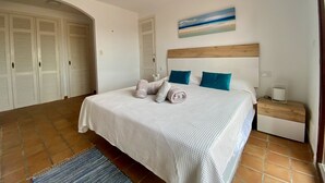 Un dormitorio con cama, mesita de noche, un cuadro y varios armarios.