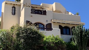Un edificio de estilo mediterráneo con fachada blanca, varios balcones y ventanas de arco.