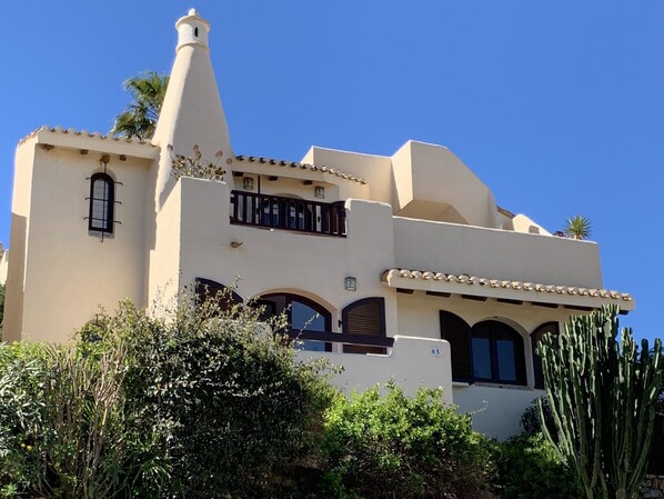 Een gebouw in mediterrane stijl, met een witte gevel, meerdere balkons en gebogen ramen.