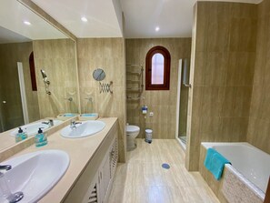 Een moderne badkamer met twee wasbakken, een toilet, een douche en een bad.