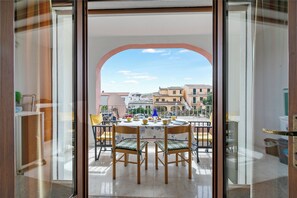 Ein Balkon mit Esstisch, Stühlen und Blick auf Gebäude im Hintergrund.
