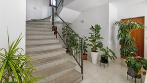 A staircase with a metal railing leading to a landing. There are several potted plants on the landing and along the staircase. - Delfino 3 Few Minutes From Sea (Loiri Porto San Paolo)