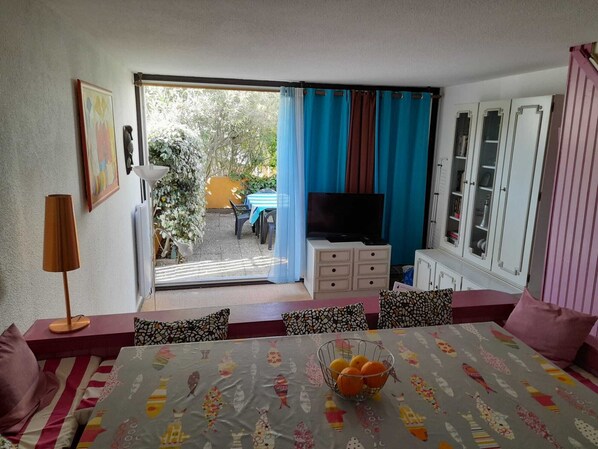 A room with a dining table, chairs, a television, and a cabinet.