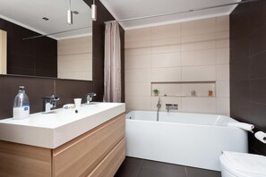 Een moderne badkamer met een wastafelmeubel met dubbele wastafel, een badkuip en een toilet.