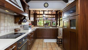 Une cuisine avec des meubles de rangement en bois, un four encastré et une fenêtre donnant sur un jardin.