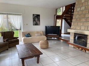 Una sala de estar con un sofá, una televisión, una chimenea de piedra y una escalera.