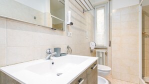 A modern bathroom with a double sink, a toilet, and a shower area.