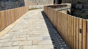 Un camino de piedra que lleva a un edificio con un muro de piedra y una cerca de madera.
