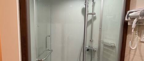 A modern shower stall with a glass door, a handheld showerhead, and a built-in seat.