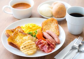 Un plato con huevos revueltos, salchicha, jamón y galletas.