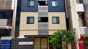 Un moderno edificio de hotel con un balcón central, varias ventanas y un letrero que indica que es el Hotel Erenoa.