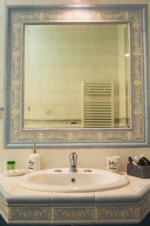 Un baño con un espejo grande, un lavabo y un perchero para toallas.