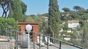 Une terrasse en bois avec une piscine, un banc et un lampadaire.