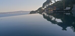 An infinity pool with a view of the sea and distant hills. - Sainte-Maxime Heated Pool Stunning view of Saint-Tropez - 2 suites (Sainte-Maxime)