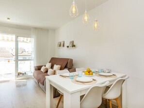A modern living room with a sofa, dining table, and hanging lights.