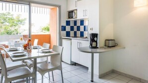 Eine moderne Küche mit weißen Schränken, einer blau-weiß karierten Spritzschutzleiste, einer Kaffeemaschine und einem Toaster auf einer kleinen Kochinsel.