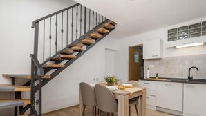 A modern kitchen with white cabinets, a black countertop, and a wooden staircase.